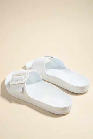 Pair of white sandals on a beige background